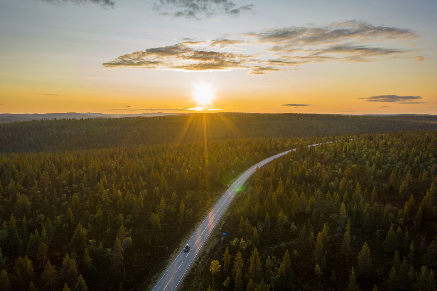 Aerial view of the midnight sun shining over a remote road